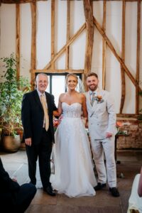 Celebrant joins the couple for a final photo at the ceremony’s close — a moment of joy and connection.
