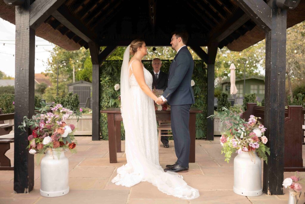 Couple exchanging vows under the thatched gazebo at The Channels Estate, Essex.