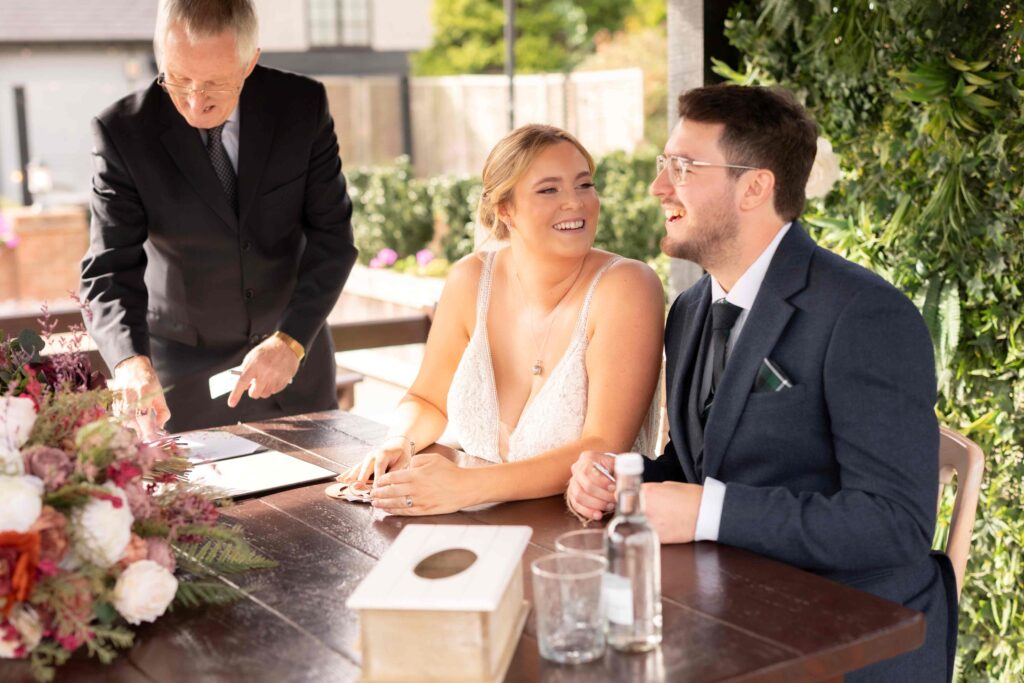 Couple sharing a quiet moment while witnesses sign the commemorative certificate at The Channels Estate.