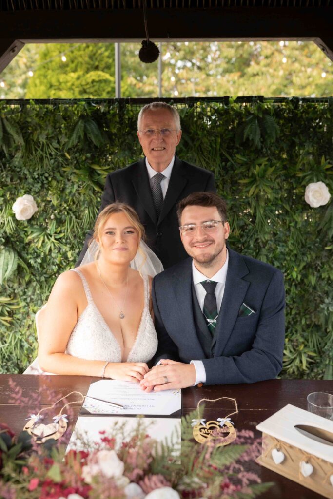 Couple posing with their commemorative certificate and celebrant at The Channels Estate, Essex.