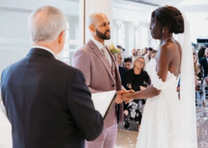 Couple exchanging vows as the celebrant leads the ceremony with guests watching.