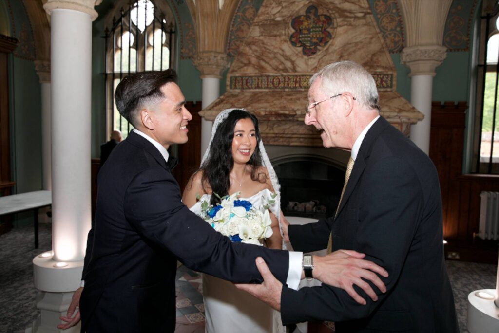 Bride and groom sharing a joyful moment with their celebrant in The Old Library at Wotton Hall in Surrey.