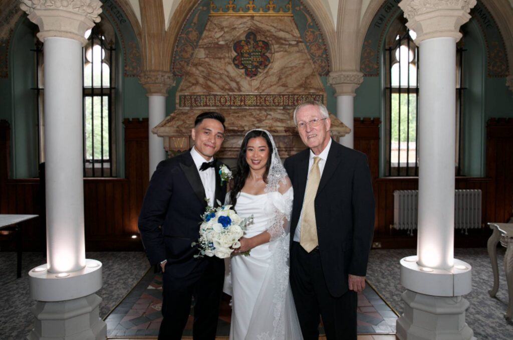 Bride and Groom with their celebrant in the ornate interior of The Old Library at Wotton Hall in Surrey.